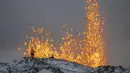 Ilmuwan dari Universitas Islandia melakukan pengukuran dan sampel dengan berdiri di punggung bukit di depan bagian aktif celah letusan gunung berapi aktif di Grindavik di Semenanjung Reykjanes Islandia, Selasa (19/12/2023). (AP Photo/Marco Di Marco)