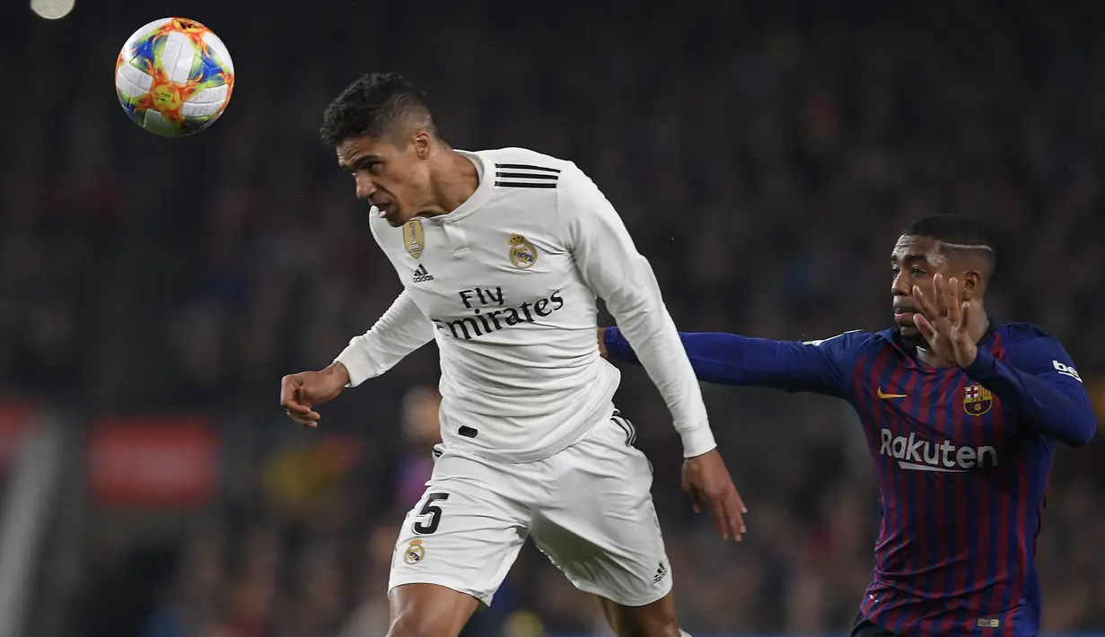 Bek Real Madrid, Raphael Varane (kiri) menyundul bola di depan gelandang Barcelona, Malcom pada laga leg pertama semifinal Copa del Rey 2018/2019 di Camp Nou Stadium, Barcelona (6/2/2019). Raphael Varane yang membela Real Madrid selama 10 musim mulai 2011/2012 hingga 2020/2021 total tampil dalam 360 laga di semua ajang dengan torehan 17 gol dan 7 assist. (AFP/Lluis Gene)
