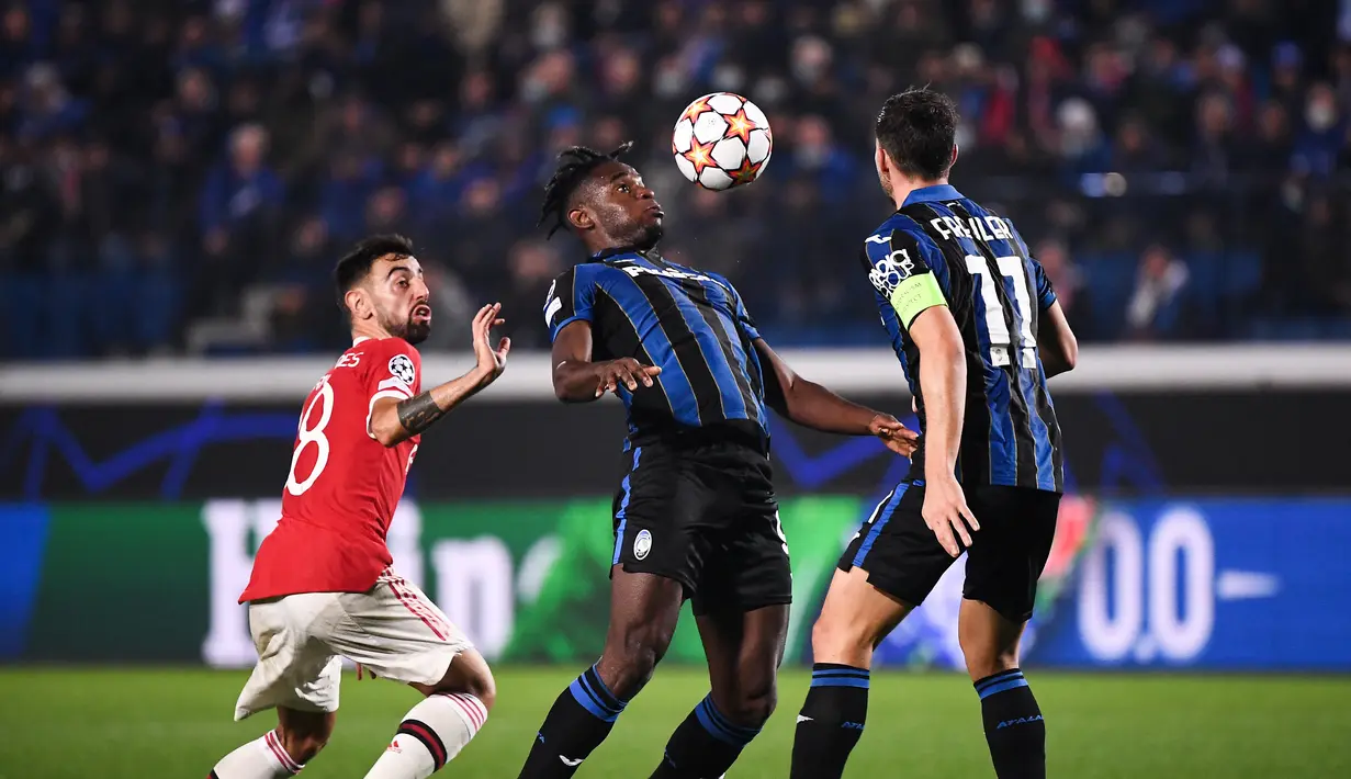 Pemain depan Atalanta, Duvan Zapata (tengah) berebut bola dengan gelandang Manchester United (MU), Bruno Fernandes pada matchday keempat Liga Champions di Stadion Gewiss, Rabu dini hari WIB (3/11/2021). Atalanta berhasil menahan imbang MU 2-2. (Marco BERTORELLO / AFP)