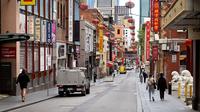 Orang-orang berjalan di jalan yang sepi di Chinatown Melbourne, ketika kota itu bersiap untuk mencabut beberapa pembatasan, Selasa (19/10/2021). Melbourne menjalani penguncian atau lockdown terpanjang di dunia, melebihi penguncian di Buenos Aires selama 234 hari. (William WEST/AFP)