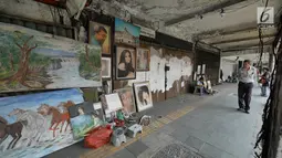 Seorang pria melihat karya lukisan di trotoar Kawasan Glodok, Jakarta, Selasa (15/5). Para pelukis ini menawarkan jasanya dengan kisaran harga Rp150 ribu sampai dengan Rp 5 juta. (Liputan6.com/Herman Zakharia)