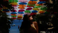 Julia Pena (19) dari Miami menikmati instalasi seni yang bernama Umbrella Sky di Coral Gables, Florida, 16 Juli 2018. Coral Gables merupakan kota ketiga di AS yang menjadi tuan rumah bagi instalasi seni yang berlangsung hingga Agustus. (AP/Brynn Anderson)
