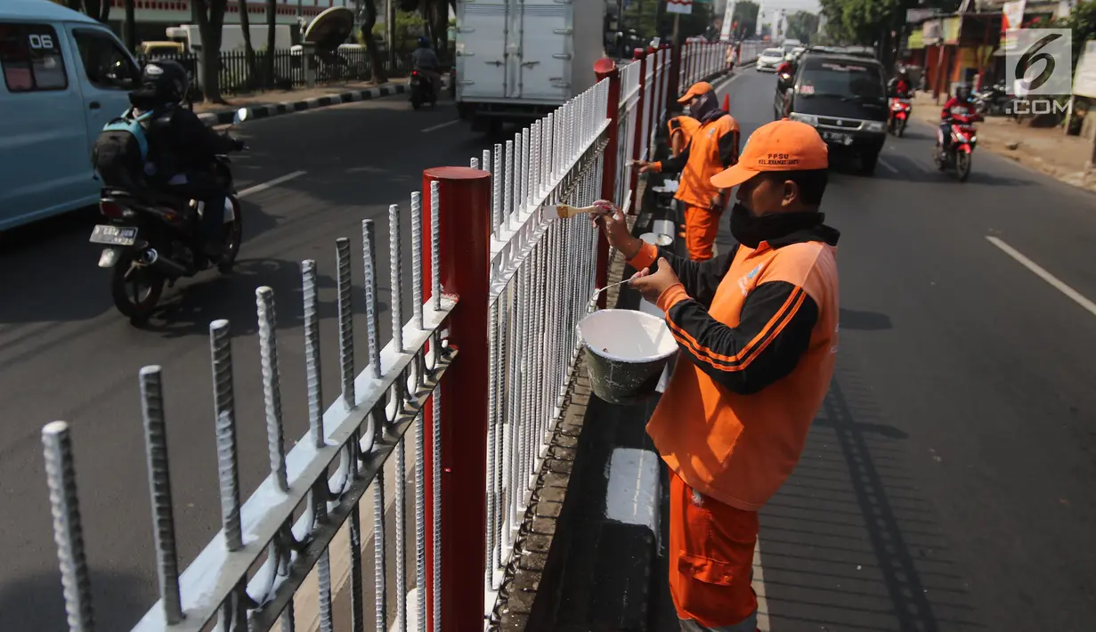 Petugas PPSU Kelurahan Kramat Jati melakukan pengecatan ulang pagar pembatas Jalan Raya Bogor, Jakarta, Selasa (17/7). Upaya penataan sekaligus mempercantik kawasan terus dilakukan jelang Asian Games dan Hari Kemerdekaan RI. (Liputan6.com/Arya Manggala)