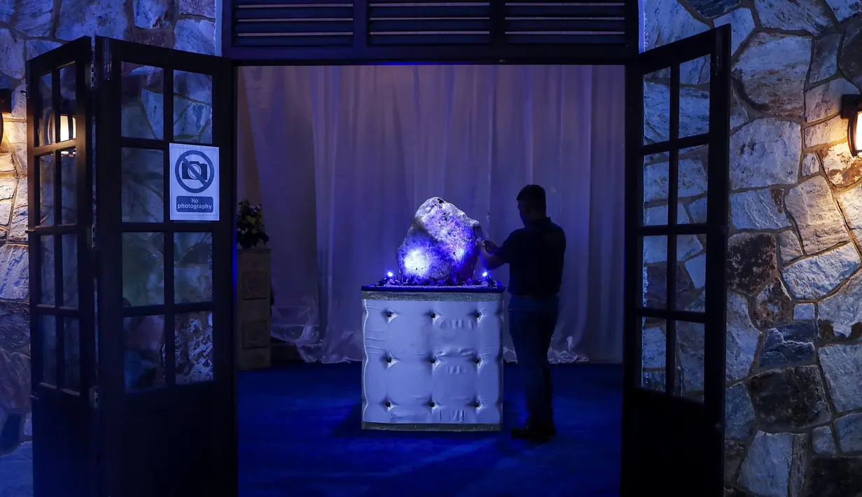 Seorang pria Sri Lanka mengambil foto safir biru korundum alami seberat 310 kilogram di Horana, sekitar 41 km dari selatan Kolombo, pada 12 Desember 2021. Kendati demikian oganisasi internasional belum mengesahkannya sebagai yang terberat di dunia. (AP Photo/Eranga Jayawardena)