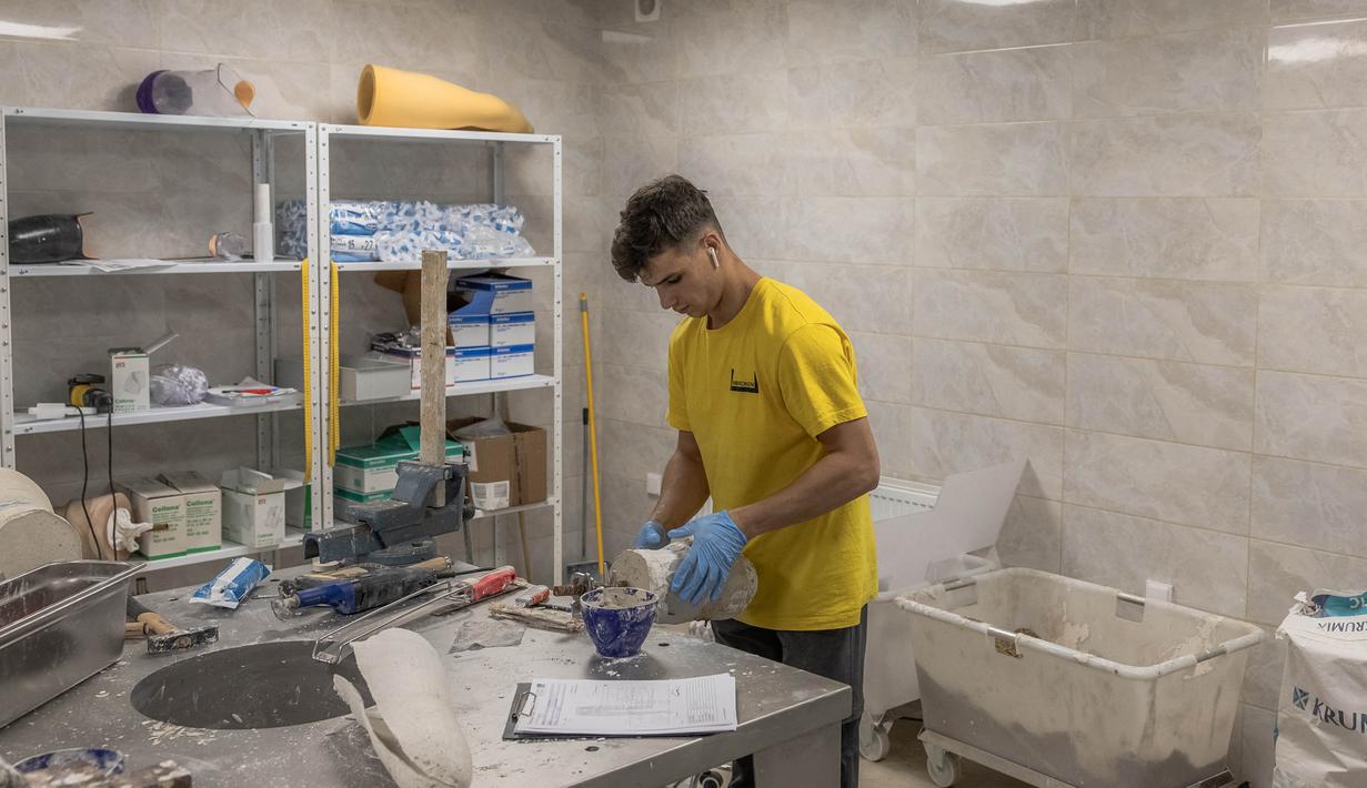 Seorang karyawan sedang bekerja untuk membuat prostesis di Pusat Rehabilitasi Nasional Unbroken di Lviv, Ukraina barat, pada 18 September 2023. (Roman PILIPEY/AFP)