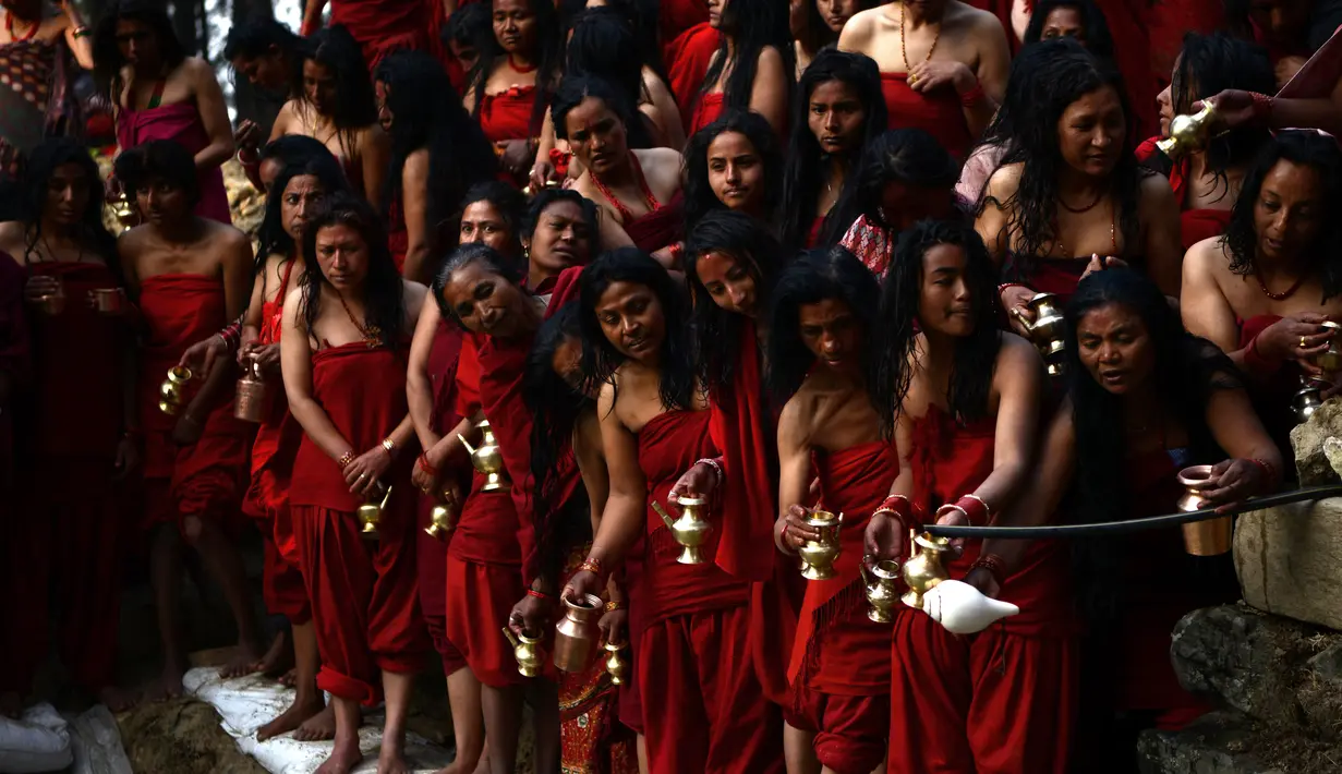Para wanita Hindu Nepal melakukan ritual mandi suci selama Festival Swasthani Brata Katha di Hutan Changu Narayan di Bhaktapur, Nepal, (8/2). Selain mandi suci, wanita nepal memanjatkan doa untuk mendapatkan suami. (AFP Photo / Prakash mathema)