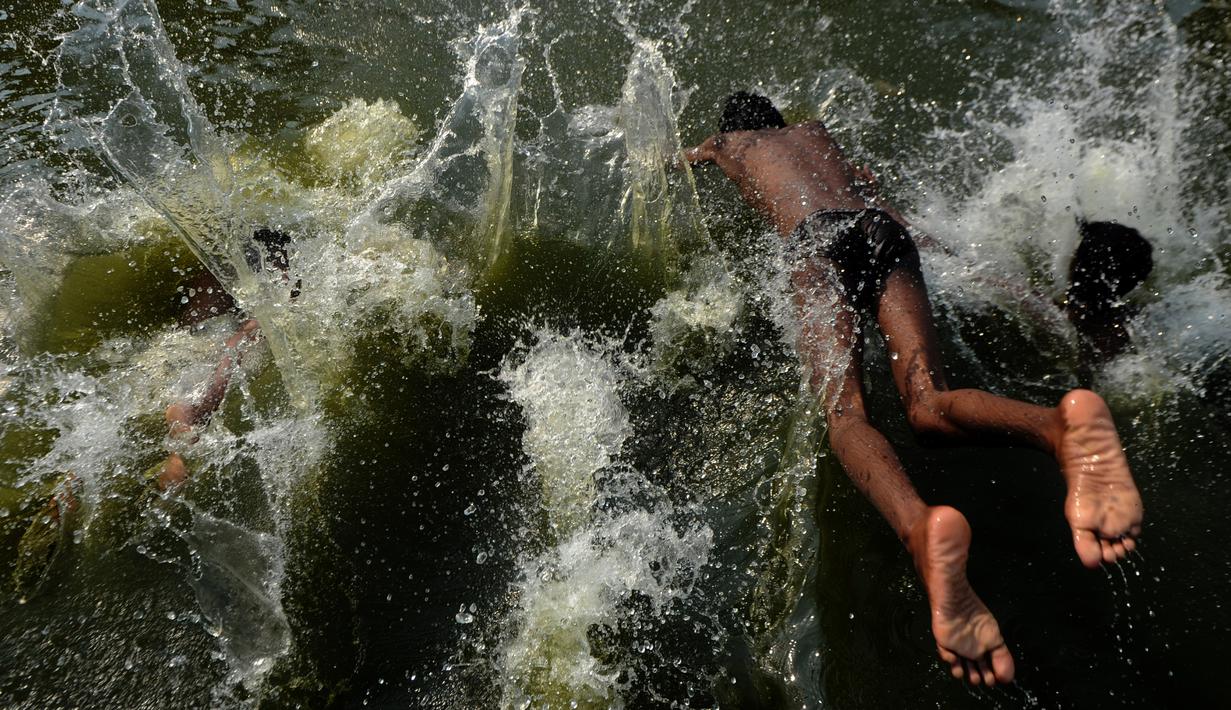 Sejumlah pria mandi di sungai yang tercemar di pinggiran Chennai, India, Rabu (5/4). Meski telah tercemar tidak menghalangi mereka untuk tetap mandi di sungai tersebut. (AFP PHOTO / ARUN SANKAR)