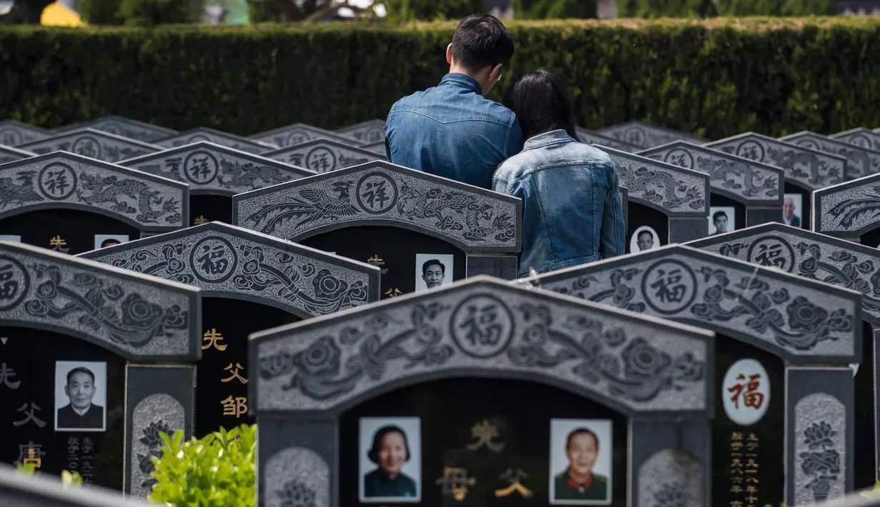Peziarah berdoa dan memberikan penghormatan di depan makam keluarganya untuk menyambut festival Ching Ming di Shanghai (3/4). Untuk orang Tionghoa, perayaan ini dilakukan untuk mengingat dan menghormati nenek moyang. (AFP/Johannes Eisele)