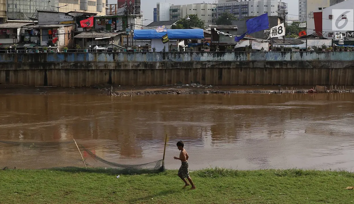 Seorang anak usai bermain sepak bola di bantaran Kanal Banjir Barat, Jakarta, Jumat (5/4). Tidak adanya lapangan menjadikan lokasi tersebut sebagai tempat bermain mereka, meskipun dalam kondisi seadanya. (Liputan6.com/Immanuel Antonius)