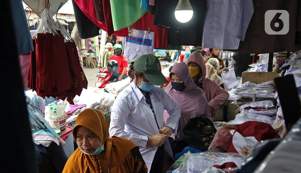 Pembeli mencoba seragam sekolah di Pasar Mester, Jakarta , Minggu (29/8/2021). Menurut pedagang, penjualan seragam sekolah kembali meningkat hingga 30 persen jelang masuk sekolah tatap muka yang dilaksanakan kembali pada 30 Agustus 2021. (Liputan6.com/Herman Zakharia)
