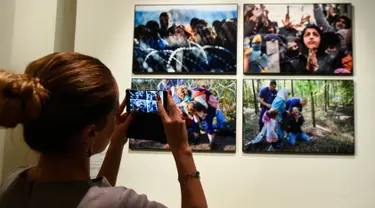 Pengunjung mengambil foto saat pameran karya fotografer Agence France-Presse (AFP) mengenai krisis migrasi di Eropa di pusat seni Bozar di Brussels (3/5). Pameran ini berjudul "Puting a Face on the Invisibles. (AFP Photo/John Thys)