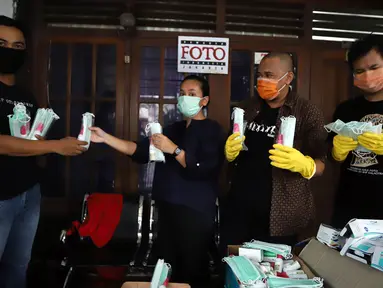 Ketua Pewarta Foto Indonesia (PFI) Reno Esnir (kedua kanan) membagikan masker dan hand sanitizer kepada jurnalis foto di Jakarta, Jumat (20/3/2020). PFI membagikan 1.000 masker dan 500 botol hand sanitizer kepada lebih dari 190 jurnalis foto di DKI Jakarta. (Foto: Dok. Pewarta Foto Indonesia)