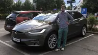 Nils Henningstad berpose di samping mobil Tesla Model X saat mengemudikan mobil listrik di stasiun pengisian umum di Oslo, Norwegia (13/07/2017). Momentum membangun mobil listrik dinilai tepat, (Lene Marie Brynildsen / Courtesy of Nils Henningstad via AP)