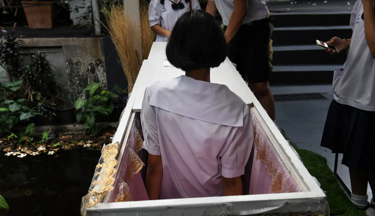 Seorang siswa remaja mencoba masuk ke dalam peti mati di Kid Mai Death Awareness Cafe, Thailand (30/3). Cafe ini menyediakan ruang pameran yang dibangun untuk mendidik masyarakat tentang kematian dan agama Buddha di Bangkok. (AFP/Lillian Suwanrumpha)