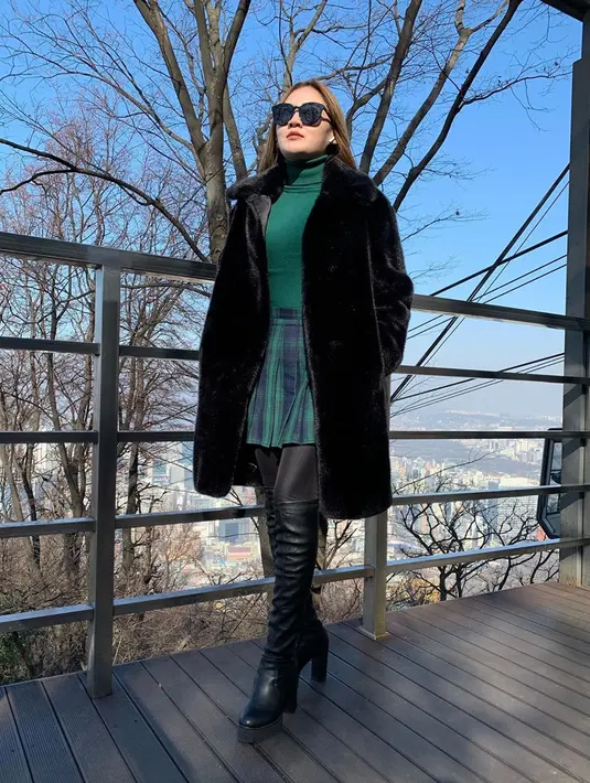Pergi berlibur ke luar negeri, wanita kelahiran 1994 ini menggunakan jaket berbulu hitam. Penampilan semakin memukau saat dipadukan dengan baju hitam dan rok mini kotak-kotak. Penampilannya pun bak Idol Korea. (Liputan6.com/IG/@nellakharisma)