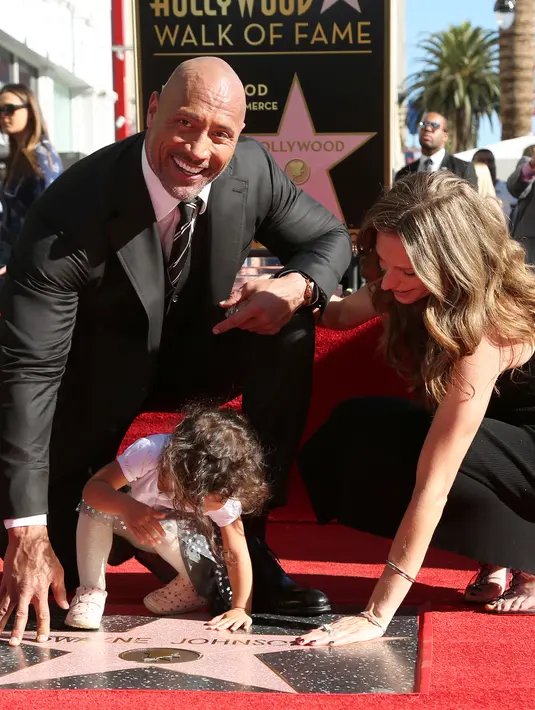 Aktor Dwayne Johnson bersama kekasihnya, Lauren Hashian dan putrinya Jasmine Johnson berpose di sebuah plakat bintang atas namanya dari Hollywood Walk of Fame di Los Angeles, Jumat (13/12). (Photo by Willy Sanjuan/Invision/AP)