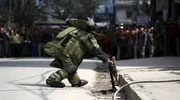 Seorang anggota tim penjinak bom saat akan mengamankan sebuah benda mencurigakan dipinggir jalan kompleks kantor Singha Durbar, Nepal, (1/3).Setelah diselidiki benda itu hanyalah sebuah alarm biasa. (REUTERS / Navesh Chitrakar)