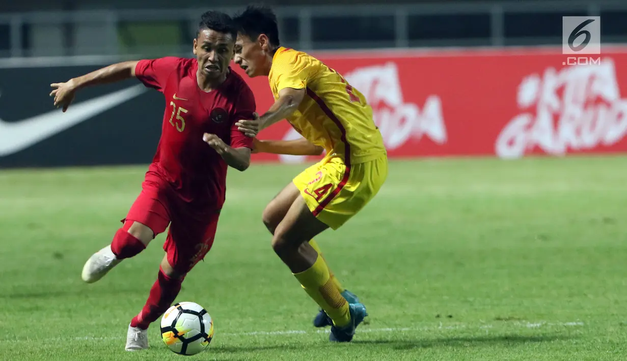 Bek Timnas Indonesia U-19. Firza Andika (kiri) berebut bola dengan pemain China U-19, Ao Chen pada PSSI 88th U-19 International Tournament di Stadion Pakansari, Selasa (25/9). Indonesia kalah 0-3. (Liputan6.com/Helmi Fithriansyah)