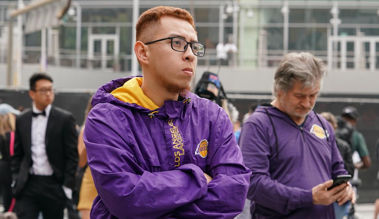 Fans LA Lakers tampak sedih usai Kobe Bryant meninggal dunia di Staples Center, Minggu (26/1/2020). Legenda basket NBA itu wafat dalam kecelakaan helikopter di Calabasas, California. (AFP/Rachel Luna)