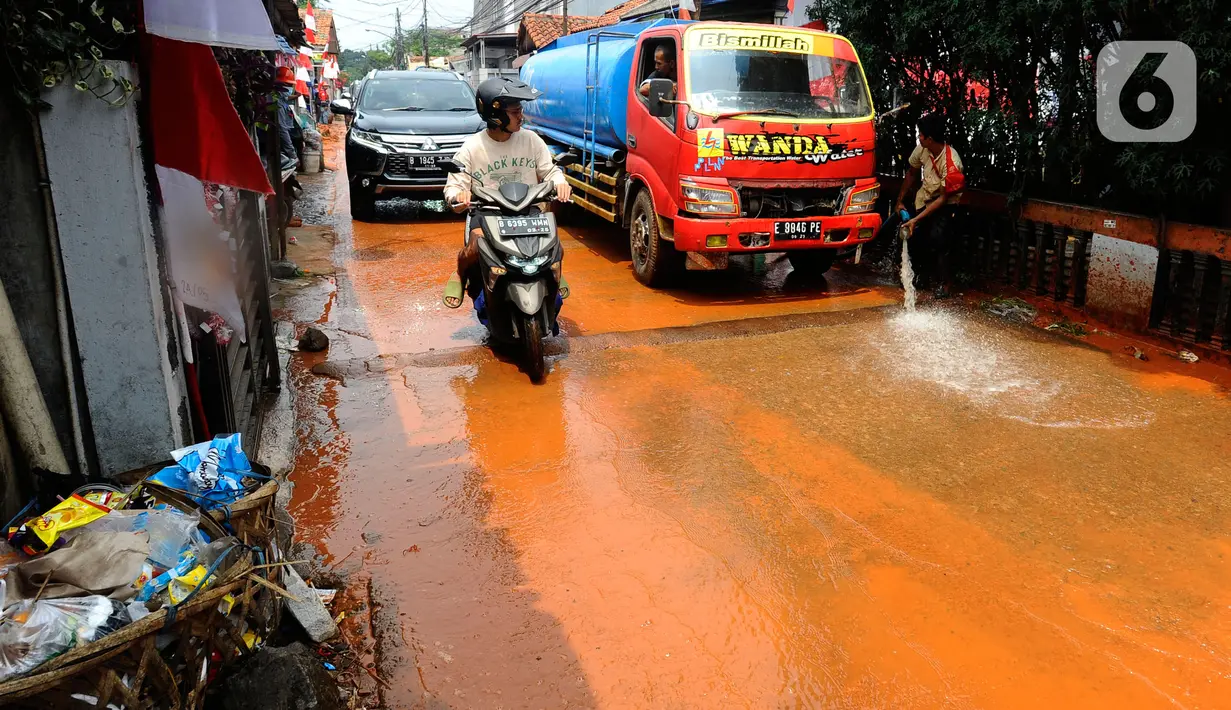 Petugas membersihkan tanah merah berlumpur   di Jalan PLN Raya Gandul  di Kecamatan Cinere, Depok, Jawa Barat, Rabu (31/8/2022). Tanah merah naik dari dalam tanah akibat  proyek pekerjaan Kabel SKTT 150kV Gandul-Kemang,  menyebabkan jalan dipenuhi tanah merah berlumpur. (merdeka.com/Arie Basuki)