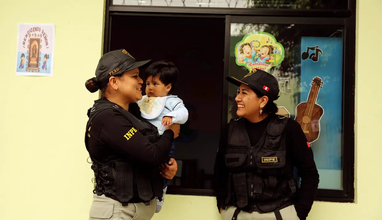 Petugas lapas menggendong seorang anak di taman kanak-kanak penjara wanita Santa Monica, Lima, Peru (31/10). (Reuters/Mariana Bazo)