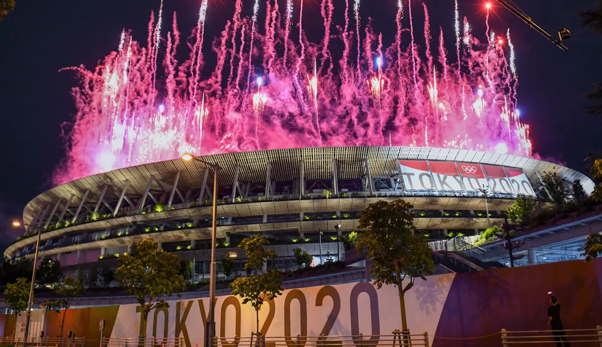 Kembang api menerangi langit di atas Olympic Stadium, saat upacara pembukaan Olimpiade Tokyo 2020, di Tokyo, Jumat (23/7/2021). Upacara pembukaan Olimpiade Tokyo yang berlangsung dalam era pandemi digelar tanpa penonton. (Photo by Kazuhiro NOGI / AFP)