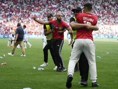 Petugas keamanan bekerja ekstra keras saat menangkap para suporter yang nekat menerobos lapangan saat Argentina berhadapan dengan Maroko pada laga grup B  Olimpiade Paris 2024. (AP Photo/Silvia Izquierdo)