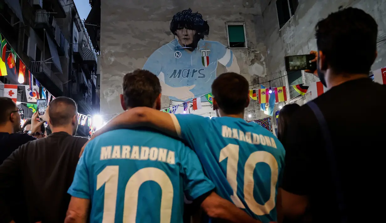 Orang-orang berkumpul di depan mural raksasa Diego Maradona saat mereka memberi penghormatan dan memperingati mendiang legenda sepak bola di hari ulang tahunnya di Naples, Italia, 30 Oktober 2022. Legenda sepak bola asal Argentina, Diego Armando Maradona yang lahir pada 30 Oktober 1960 meninggal pada 25 November 2020. (Alessandro Garofalo/LaPresse via AP)