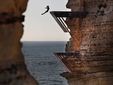 Peserta melompat dari batu karang laut 'Raouche' yang terkenal dalam kompetisi Red Bull Cliff Diving World Series di Beirut, Lebanon, 14 Juli 2019. Sebanyak 40 atlet terdiri dari 10 wanita dan 14 pria yang berasal dari 18 negara melakukan lompatan dari ketinggian 21 - 27 meter. (AP/Hussein Malla)