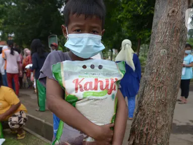Seorang anak membawa beras seusai pembagian sembako di TPU Malaka, Pondok Kopi, Jakarta, Jumat (4/3/2022). Pembagian sejumlah sembako secara gratis yang diperuntukan bagi kaum duafa ini berupa beras dan minyak goreng. (merdeka.com/Imam Buhori)