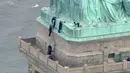 Petugas kepolisian membujuk seorang wanita yang nekat memanjat Patung Liberty di New York, Rabu (4/7). Aksi protes wanita bernama Therese Okoumou ini telah memicu ketegangan dengan para petugas berwenang selama hampir empat jam. (AFP/PIX11 News/HO)