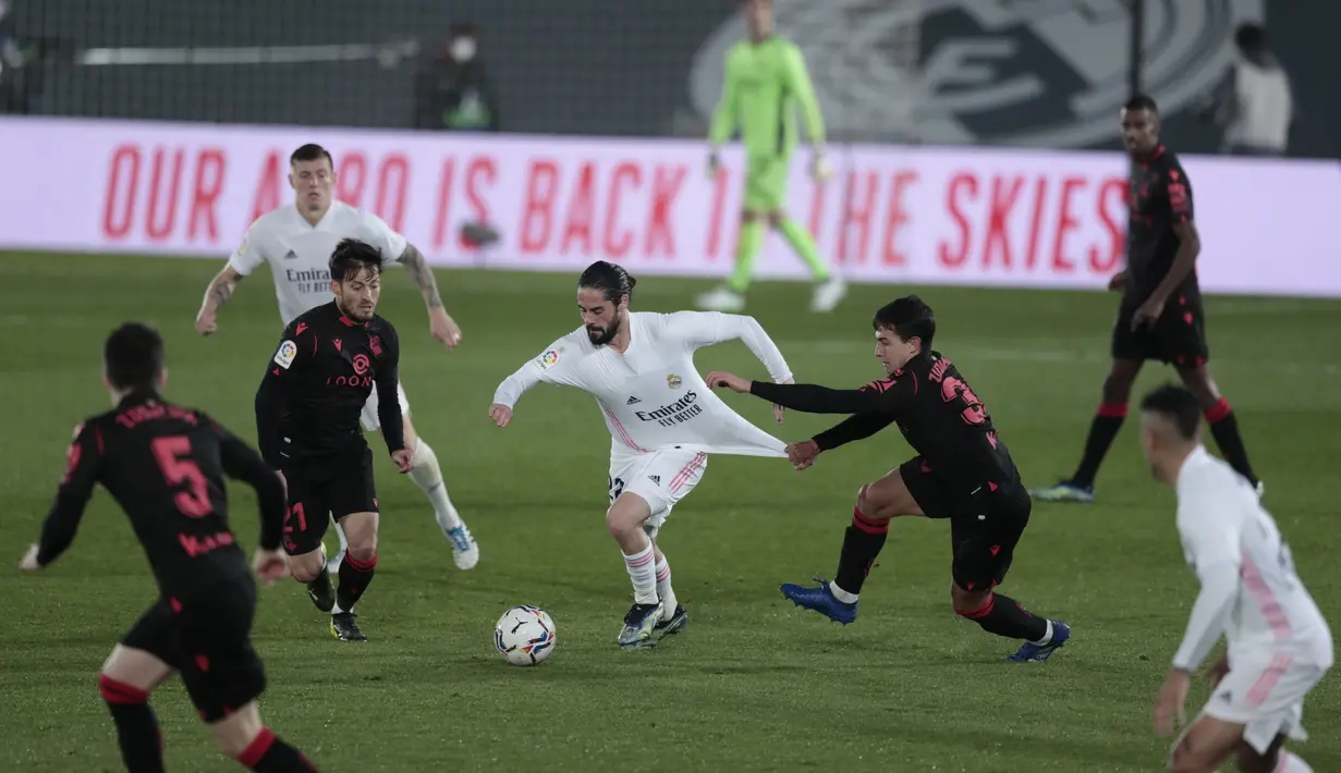 Gelandang Real Madrid, Isco (tengah) membawa bola dari kawalan pemain Real Sociedad, Martin Zubimendi pada pertandingan lanjutan La Liga Spanyol di stadion Alfredo di Stefano di Madrid, Spanyol, Selasa (2/3/2021). Real Madrid bermain imbang atas Real Sociedad 1-1. (AP Photo/Bernat Armangue)