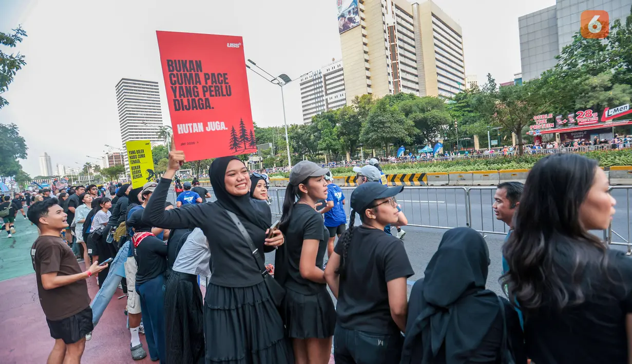 Seorang penonton membawa poster bertema kebakaran hutan dan lahan (karhutla) saat Jakarta Running Festival (JRF) 2026 di sepanjang lintasan Jalan Jenderal Sudirman, Jakarta, Sabtu (24/10/2026). (KLY/Budy Santoso)
