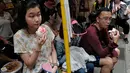 Sejumlah warga memakan roti atau bun saat perayaan Festival Cheung Chau Bun di Hong Kong (5/3). Festival ini diadakan di pulau kecil yang berada sekitar 10 kilometer dari Pulau Hong Kong yang bernama Pulau Cheung Chau. (AP Photo/Vincent Yu)