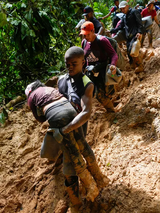 Seorang migran Haiti yang menggendong seorang anak saat penyeberangan Celah Darien dari Kolombia ke Panama Sabtu, (15/10/2022). Perjalanan Kelompok Imigran tersebut berharap mencapai Amerika Srikat (AS).(Fernando Vergara/AP)