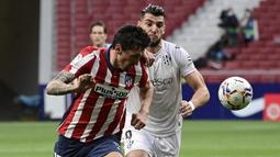 Bek Atletico Madrid, Stefan Savic (kiri) berebut bola dengan striker SD Huesca, Rafa Mir dalam laga lanjutan Liga Spanyol 2020/2021 pekan ke-32 di Wanda Metropolitano Stadium, Madrid, Kamis (22/4/2021). Atletico menang 2-0 atas SD Huesca. (AFP/Javier Soriano)
