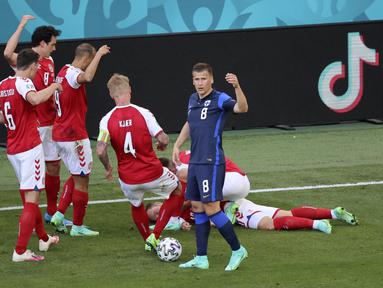 Para pemain Denmark mendatangi rekannya Christian Eriksen yang pingsan pada laga Denmark vs Finlandia di Grup B Euro 2020 di Parken Stadium, Copenhagen, Sabtu (12/6/2021). Eriksen tiba-tiba terjatuh dan kehilangan kesadaran saat hendak menyambut lemparan ke dalam. (Wolfgang Rattay/Pool via AP)