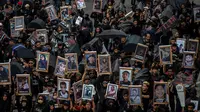 Pendukung sepak bola mengikuti aksi unjuk rasa memperingati 40 hari Tragedi Kanjuruhan, di depan balai kota Malang, Jawa Timur, Kamis (10/11/2022). Mereka membawa sejumlah keranda jenazah dengan foto-foto korban tragedi Kanjuruhan, dan poster berisi tuntutan. (JUNI KRISWANTO / AFP)