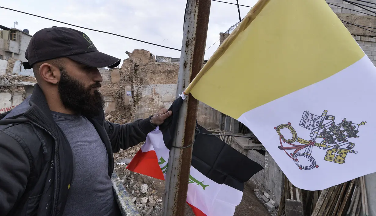 Pekerja mengibarkan bendera Irak dan Takhta Suci Vatikan di tiang-tiang jalan di kota Mosul, Irak, Kamis (4/3/2021). Pemimpin Tertinggi Umat Katolik Paus Fransiskus memulai kunjungan bersejarah ke Irak pada Jumat (5/3), meskipun menghadapi pandemi Covid-19 dan ancaman keamanan. (Zaid AL-OBEIDI/AFP)