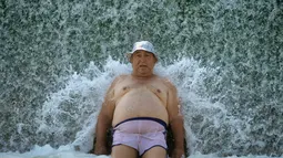 Seorang pria mendinginkan tubuhnya di sebuah sungai di Buzau, Rumania, Minggu, 6 Agustus 2017. Gelombang panas dengan suhu ekstrim hingga 42 derajat Celsius (107,6 Fahrenheit) melanda Rumania. (AP Photo / Andreea Alexandru)