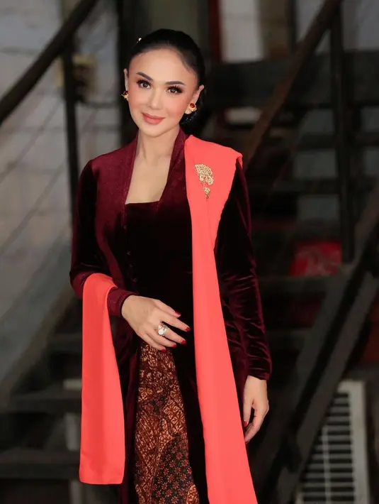 Yuni Shara mengenakan kebaya jerau tanpa motif yang dipadukan dengan selendang warna bangbang dan kain jarit. Sebuah aksesoris keemasan dari Tulola bertengger di selendangnya. Penampilan Yuni Shara disempurnakan dengan riasan wajah dari Anggun Az Zaky dan sanggul berukuran besar. Tampak paripurna sekaligus elegan, jauh dari kesan menor. (Foto: Dok. Instagram @yunishara36)
