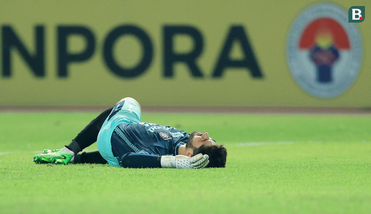 Kiper Bali United, Adilson Maringa, tergeletak di lapangan saat melawan Persija Jakarta pada laga pekan ke-13 BRI Liga 1 2023/2024 di Stadion Patriot Candrabhaga, Bekasi, Minggu (24/9/2023). (Bola.com/M Iqbal Ichsan)