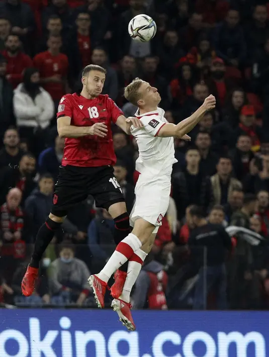 Bek Albania Ardian Ismajli dan penyerang Polandia Adam Buksa  melompat saat berebut bola pada lanjutan Kualifikasi Piala Dunia 2022, di Air Albania Stadium, Rabu (13/10/2021) dini hari WIB.  Kemenangan Polandia 1-0 atas Albania diwarnai aksi pelemparan botol oleh suporter. (AP Photo/Franc Zhurda)
