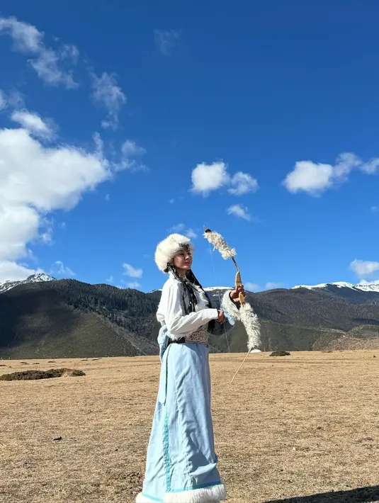 Outfit yang dikenakan Kirana memadukan coat berbulu dan cheongsam yang trendy dengan belt emas [@kiranalarasati]