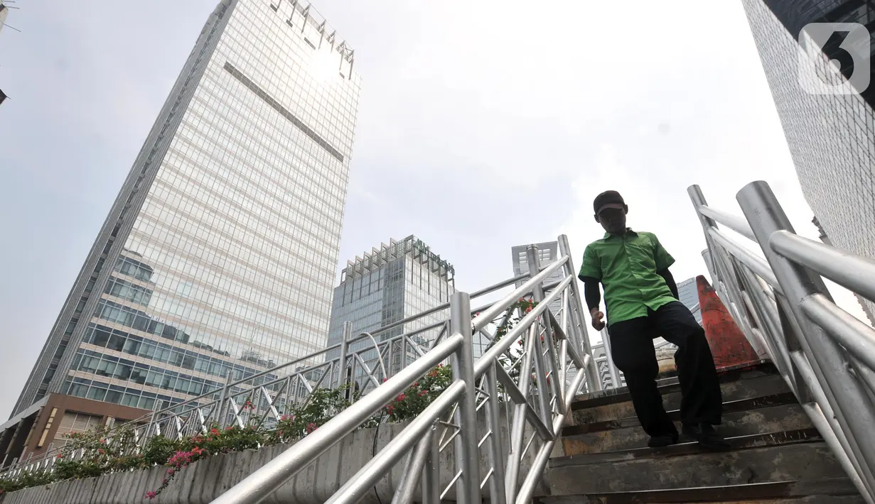 Pejalan kaki melintas di jembatan penyeberangan orang (JPO) yang tidak beratap di jalan Sudirman, Jakarta, Rabu (6/11/2019). Pemprov DKI melalui Dinas Bina Marga mencopot atap JPO Sudirman agar pejalan kaki dapat menikmati pemandangan gedung-gedung pencakar langit. (merdeka.com/Iqbal Nugroho)