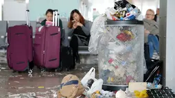 Tumpukan sampah terlihat di dekat penumpang yang menunggu jadwal penerbangan di Bandara Barcelona, Spanyol, Kamis (1/12). Para petugas kebersihan melakukan aksi protes mengotori ruangan bandara dengan sampah sobekan kertas. (REUTERS/Albert Gea)