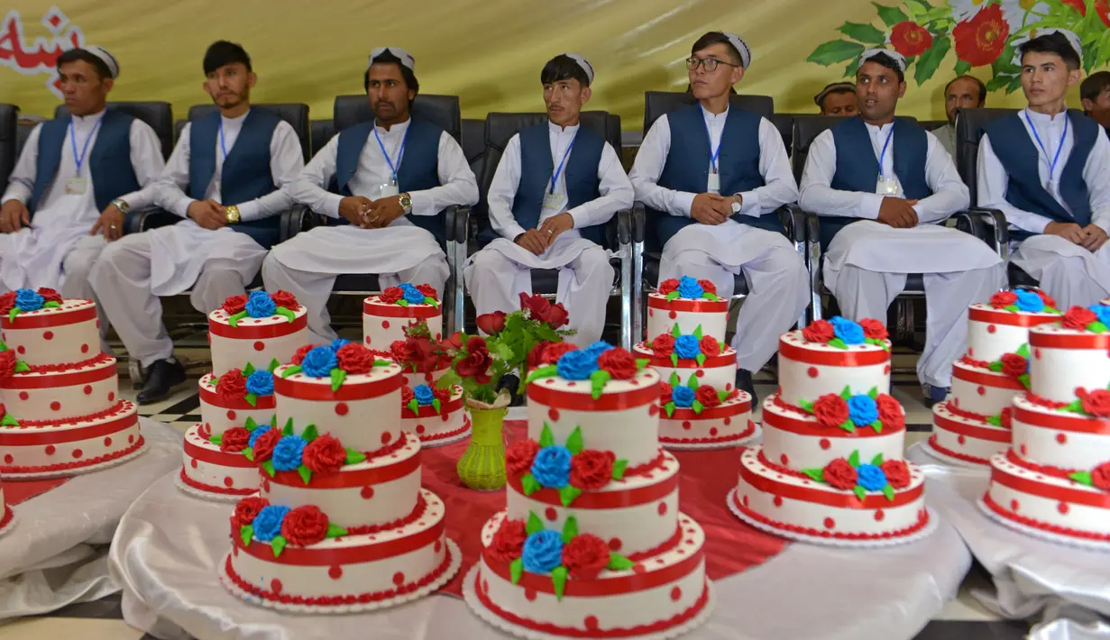 Para pengantin pria duduk dalam aula pernikahan saat mereka menunggu dimulainya upacara pernikahan massal di Kabul, Afghanistan, 13 Juni 2022. Puluhan wanita Afghanistan yang disembunyikan dalam selendang hijau tebal dinikahkan dalam pernikahan massal yang ketat di Kabul. (Sahel ARMAN/AFP)
