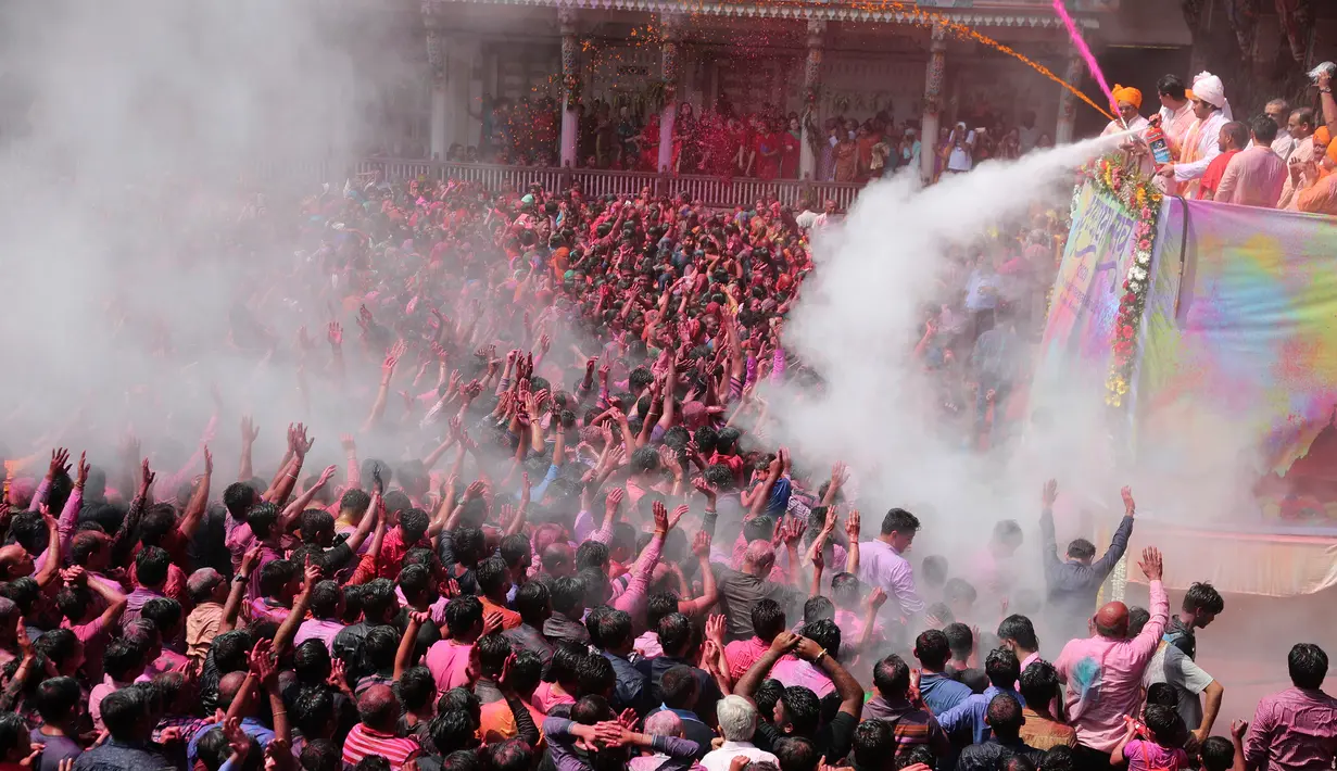 Umat Hindu bersorak ketika bubuk berwarna dan air disemprotkan kepada mereka saat Festival Holi di Kuil Swaminarayan, Ahmedabad, India, Selasa (10/3/2020). Festival Holi menandai datangnya musim semi di India. (AP Photo/Ajit Solanki)