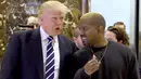 Presiden AS terpilih, Donald Trump dan Kanye West bebrincang sambil berjalan di lobi Trump Tower, New York, Selasa (13/12). Trump dan Kanye West melakukan pertemuan tertutup untuk membahas masalah multikultural. (TIMOTHY A. CLARY/AFP)
