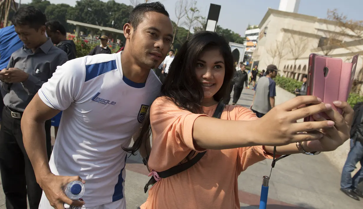 Kapten Persib, Atep berselfie dengan seorang fans usai latihan di Alun-alun Kota Bandung, Jawa Barat, Kamis (10/9/2015). (Bola.com/Vitalis Yogi Trisna)